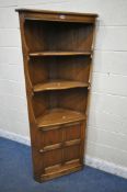 AN ERCOL ELM OLD COLONIAL CORNER CUPBOARD, with two fixed shelves, above a single cupboard door