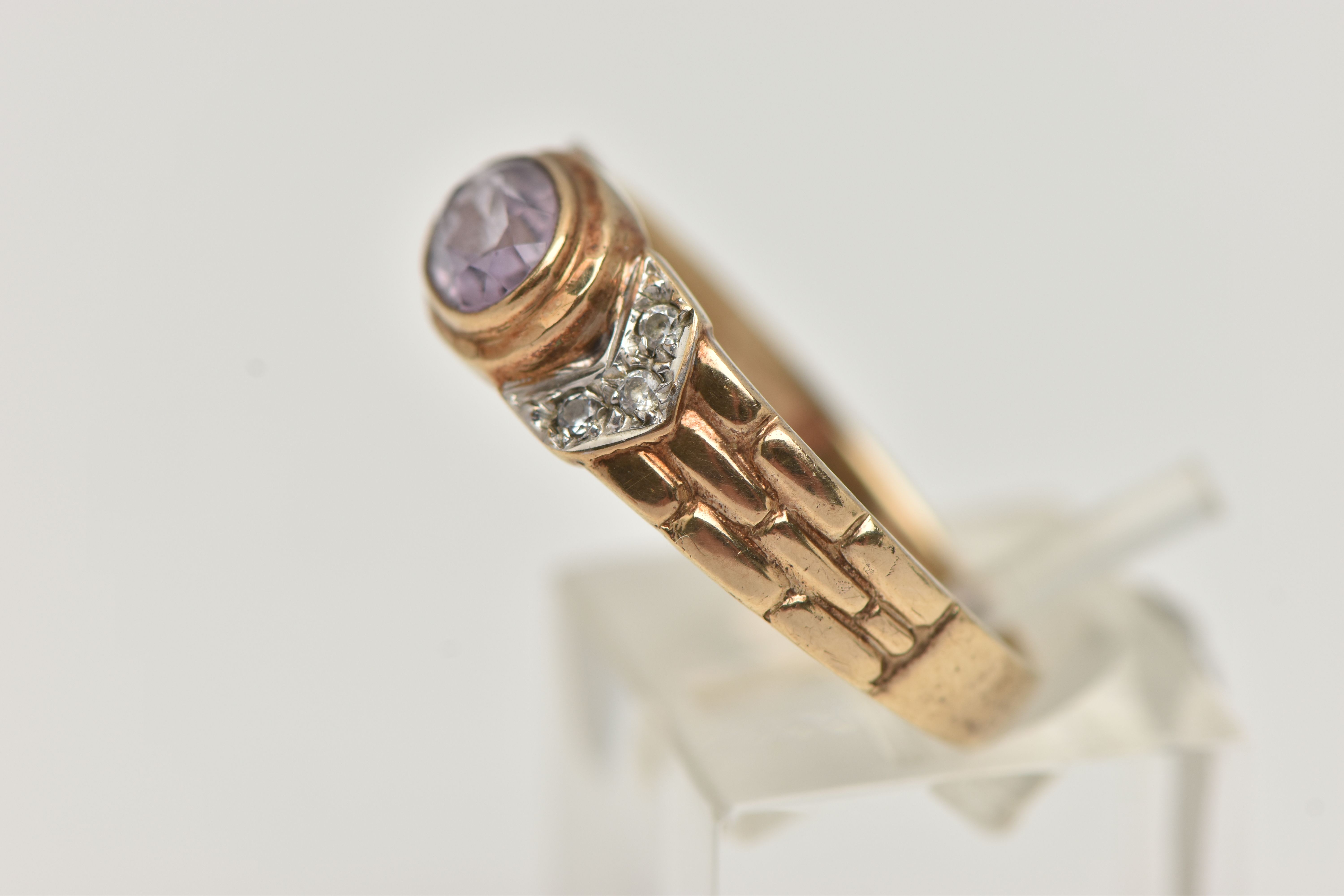 A 9CT GOLD AMETHYST RING, the central oval amethyst in a collet setting, flanked by colourless - Image 2 of 4
