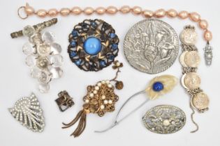AN ASSORTMENT OF JEWELLERY, to include five brooches, a white metal charm, a clip, a coin bracelet