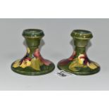 A PAIR OF MOORCROFT POTTERY 'HIBISCUS' PATTERN CANDLESTICKS, yellow and red Hibiscus flowers on a