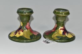 A PAIR OF MOORCROFT POTTERY 'HIBISCUS' PATTERN CANDLESTICKS, yellow and red Hibiscus flowers on a