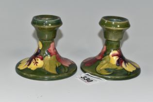 A PAIR OF MOORCROFT POTTERY 'HIBISCUS' PATTERN CANDLESTICKS, yellow and red Hibiscus flowers on a