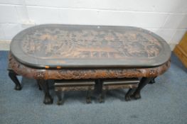 AN ORIENTAL HARDWOOD HEAVILY CARVED NESTS OF SEVEN TABLES, the large oval table depicting battle