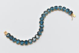 A 9CT YELLOW GOLD TOPAZ BRACELET, designed as a series of approximately twenty-three oval blue
