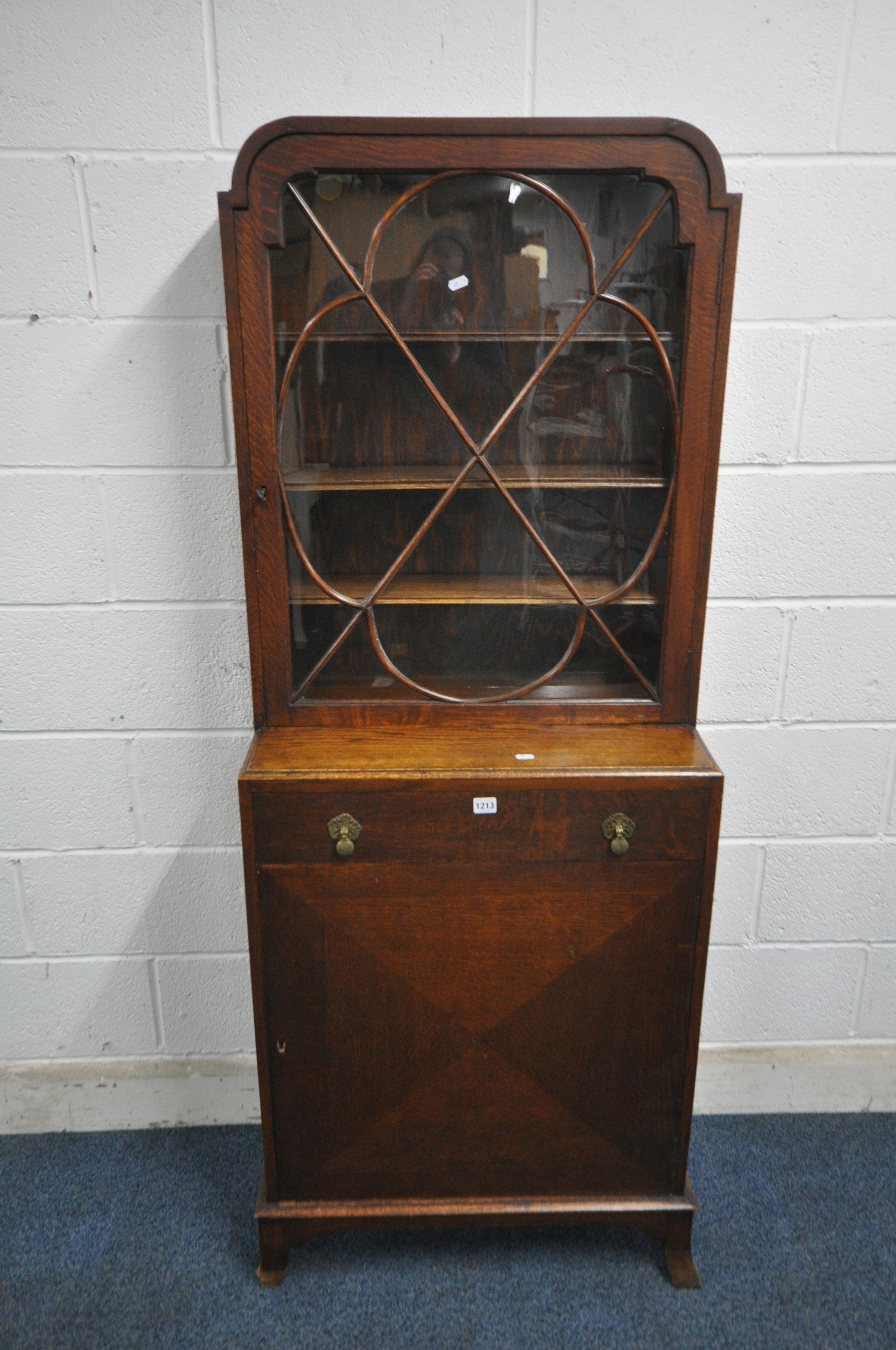 A 20TH CENTURY OAK CABINET, the single glazed door enclosing three adjustable shelves, above a