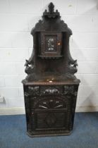 AN EARLY 20TH CENTURY OAK CARVED CORNER CUPBOARD, depicting faces, birds, foliate and geometric