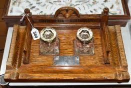 A VICTORIAN OAK DESK STAND, complete with two glass ink wells, bears a white metal inscription