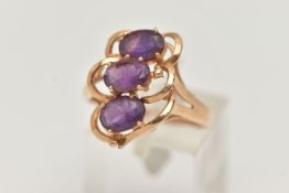A YELLOW METAL AMETHYST THREE STONE RING, set with three oval cut amethyst, each four claw set to an