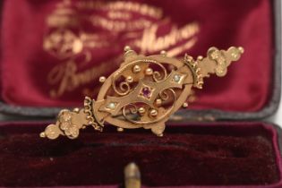 A BOXED 9CT GOLD BROOCH, open work brooch set with a small circular cut ruby and two small split