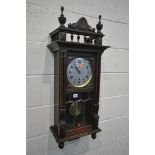 AN EARLY 20TH CENTURY WALL CLOCK, with finals and spindles above a full length door enclosing a