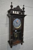 AN EARLY 20TH CENTURY WALL CLOCK, with finals and spindles above a full length door enclosing a