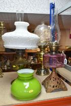 THREE OIL LAMPS AND SHADES, comprising a lamp with a pierced cast iron base and cranberry glass