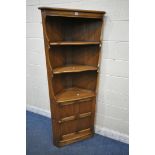AN ERCOL ELM OLD COLONIAL CORNER CUPBOARD, with two fixed shelves, above a single cupboard door
