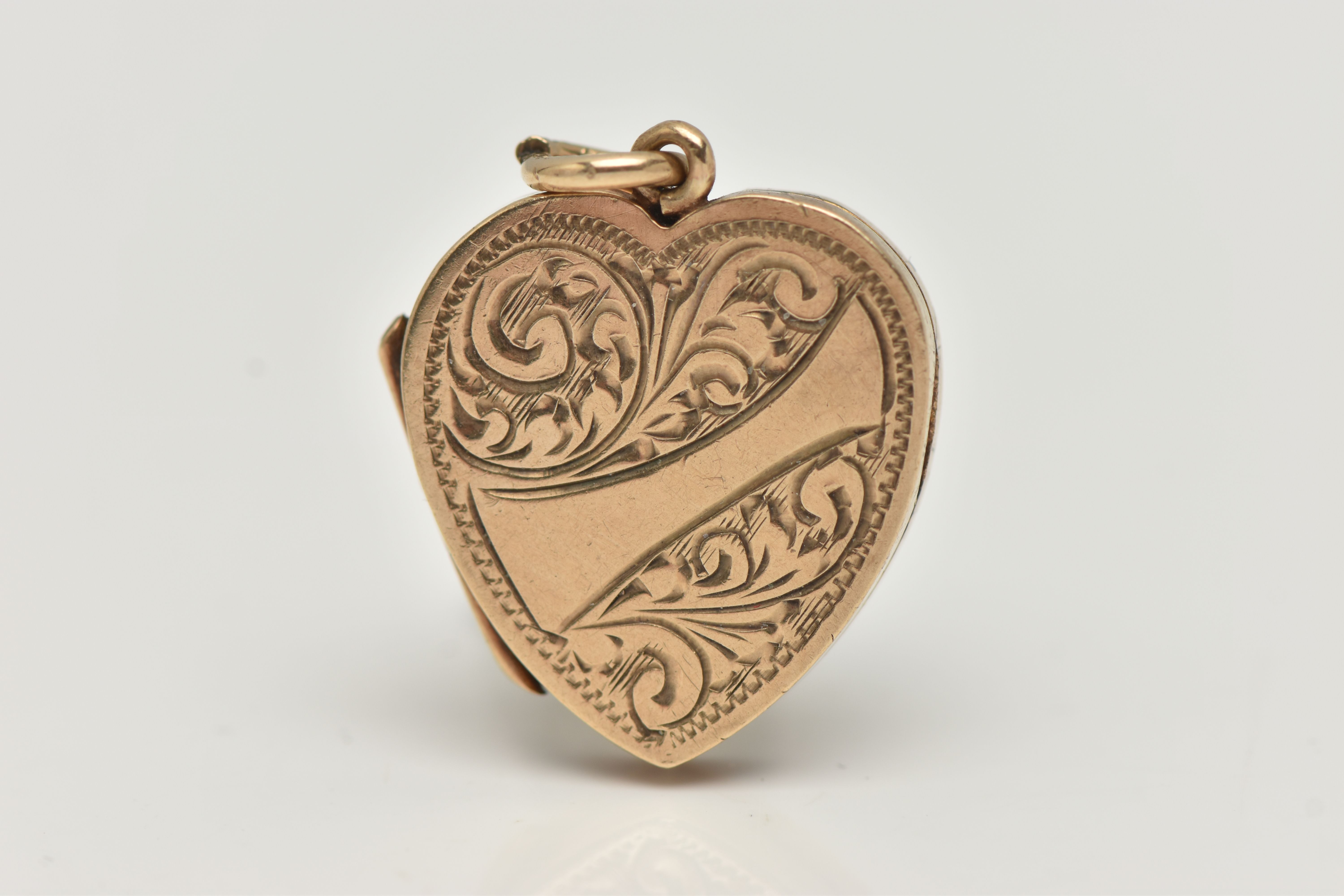 A 9CT GOLD LOCKET, heart form with etched scrolling acanthus detail and a vacant banner style