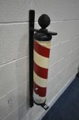 A 20TH CENTURY PAINTED BARBERS POLE, mounted on a cast iron wall hanging frame, height 89cm (