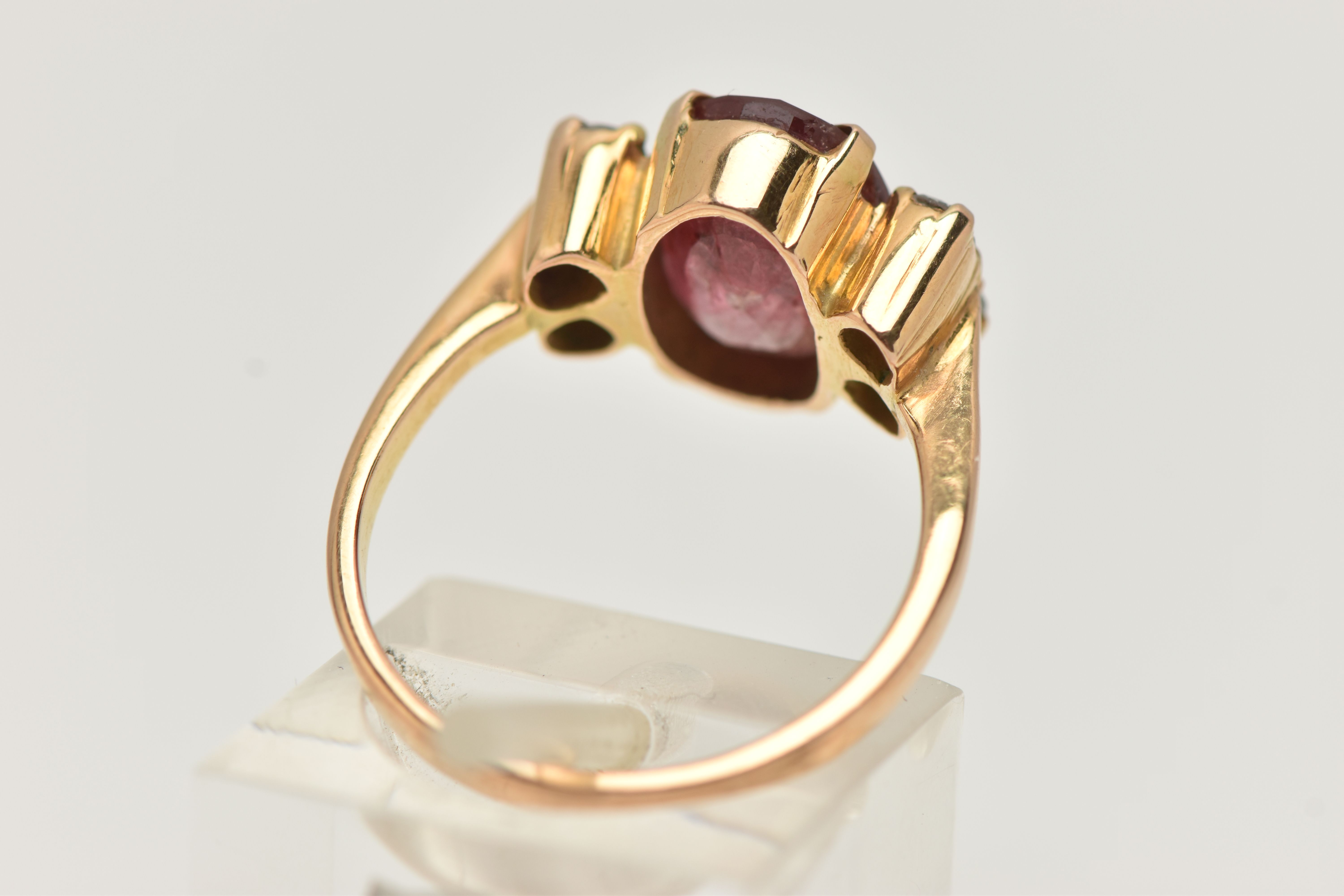 A YELLOW METAL FIVE STONE RING, centering on an oval cut heavily fracture filled red corundum, in - Image 3 of 4