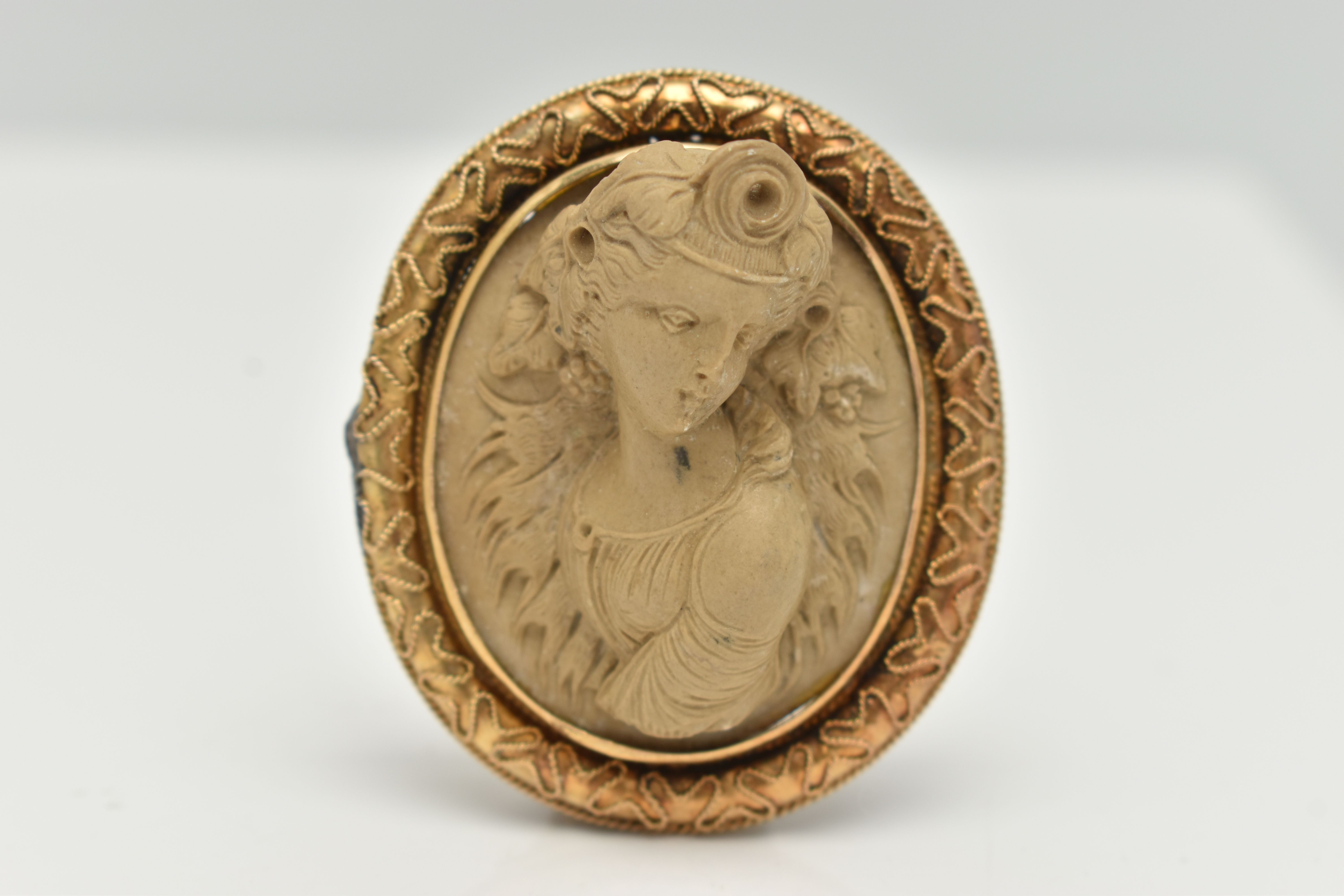 A YELLOW METAL, HIGH RELIEF LAVA CAMEO BROOCH, of an oval form, depicting a lady in profile,