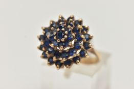 A SAPPHIRE CLUSTER RING, designed as a tiered cluster of circular sapphires in claw settings,