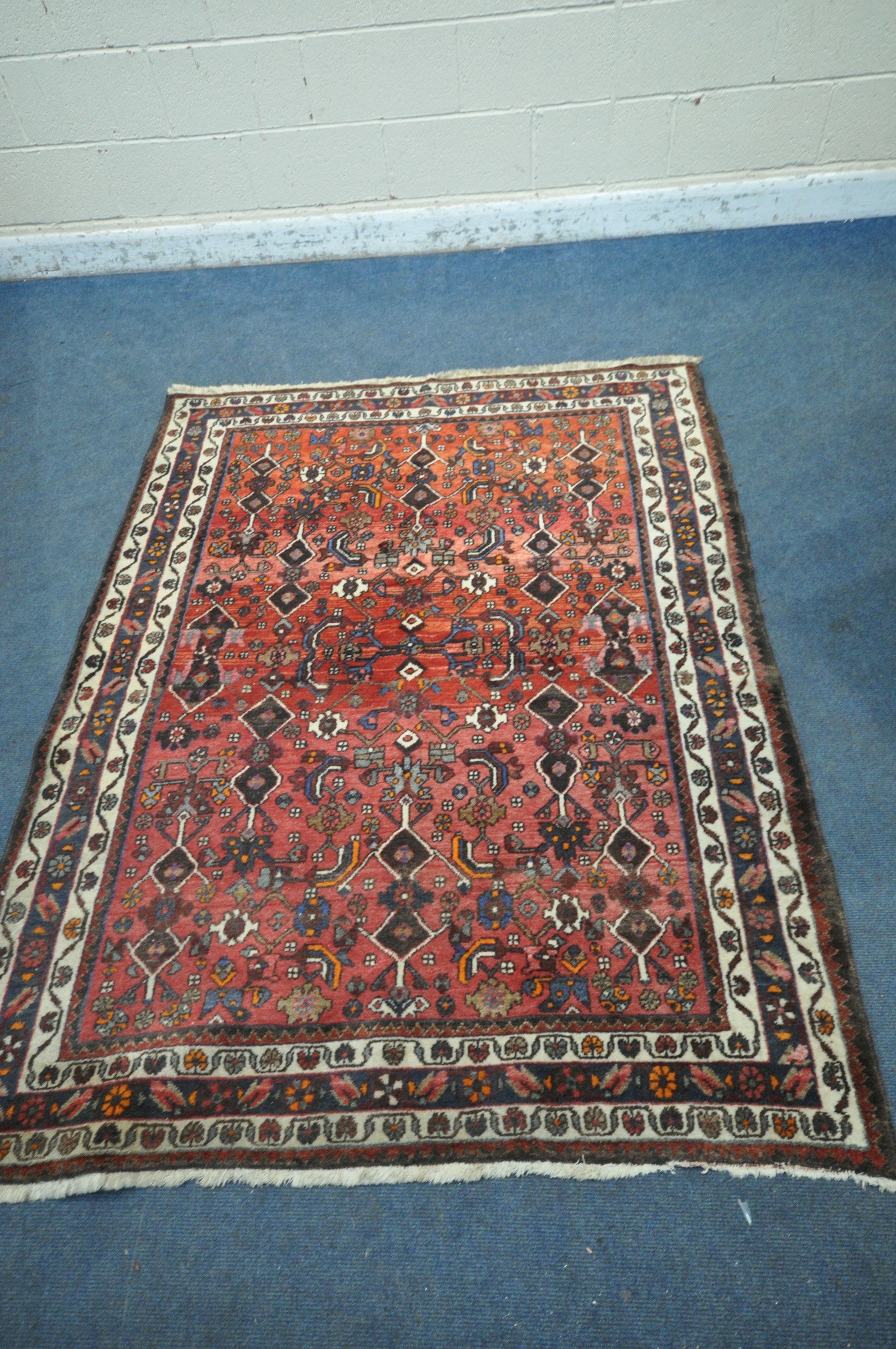 A RED GROUND WOOLLEN RUG, with repeating geometric patterns and multi-strap border, 198cm x 194cm (