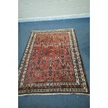 A RED GROUND WOOLLEN RUG, with repeating geometric patterns and multi-strap border, 198cm x 194cm (