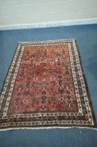 A RED GROUND WOOLLEN RUG, with repeating geometric patterns and multi-strap border, 198cm x 194cm (