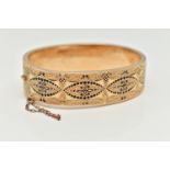 A YELLOW METAL HINGED BANGLE, wide bangle decorated with a black enamel pattern with textured