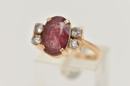 A YELLOW METAL FIVE STONE RING, centering on an oval cut heavily fracture filled red corundum, in