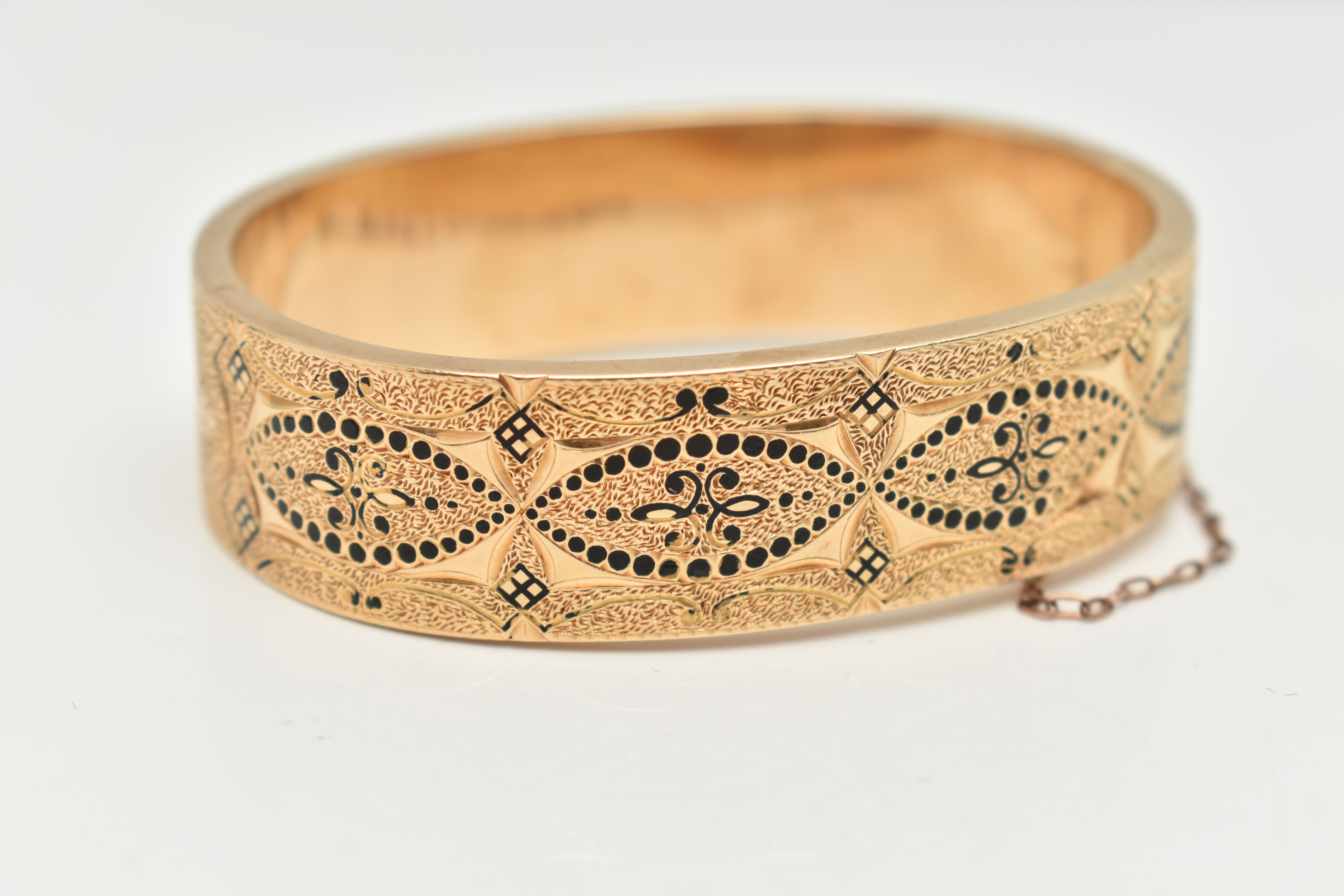 A YELLOW METAL HINGED BANGLE, wide bangle decorated with a black enamel pattern with textured - Image 3 of 3