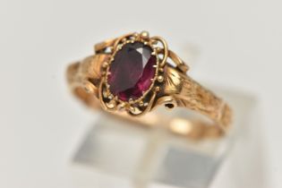 A VICTORIAN YELLOW METAL GARNET RING, centering on an oval cut garnet, claw set, the reverse of