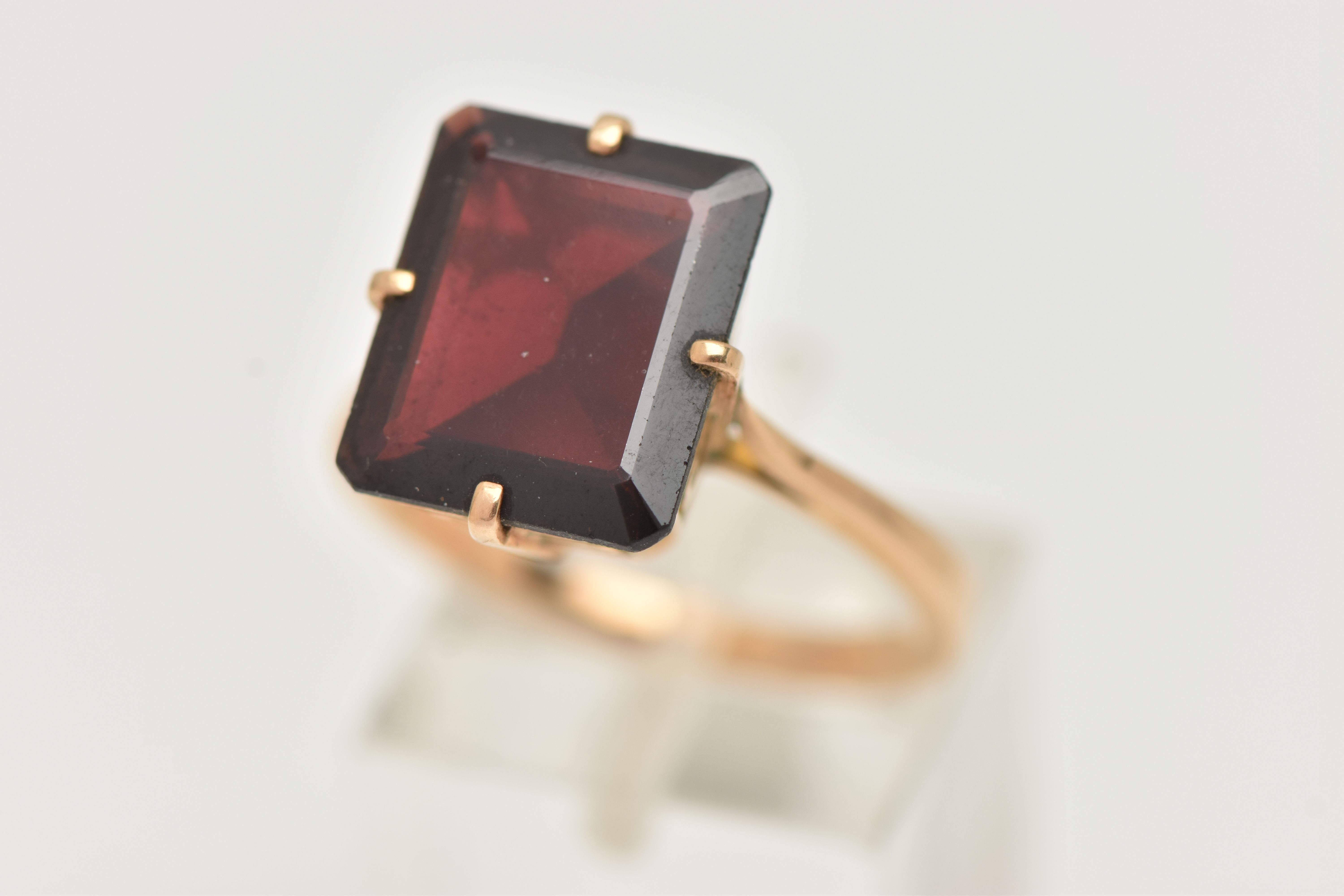 A GARNET DRESS RING, a large rectangular cut garnet, approximate length 13mm x width 11mm, four