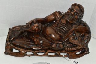 AN ORIENTAL CARVED HARDWOOD FIGURE OF A RECLINING IMMORTAL WITH DRAGON, on a separate carved