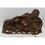 AN ORIENTAL CARVED HARDWOOD FIGURE OF A RECLINING IMMORTAL WITH DRAGON, on a separate carved