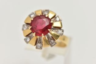 A YELLOW METAL GEM SET DRESS RING, centering on a large circular cut garnet topped red paste