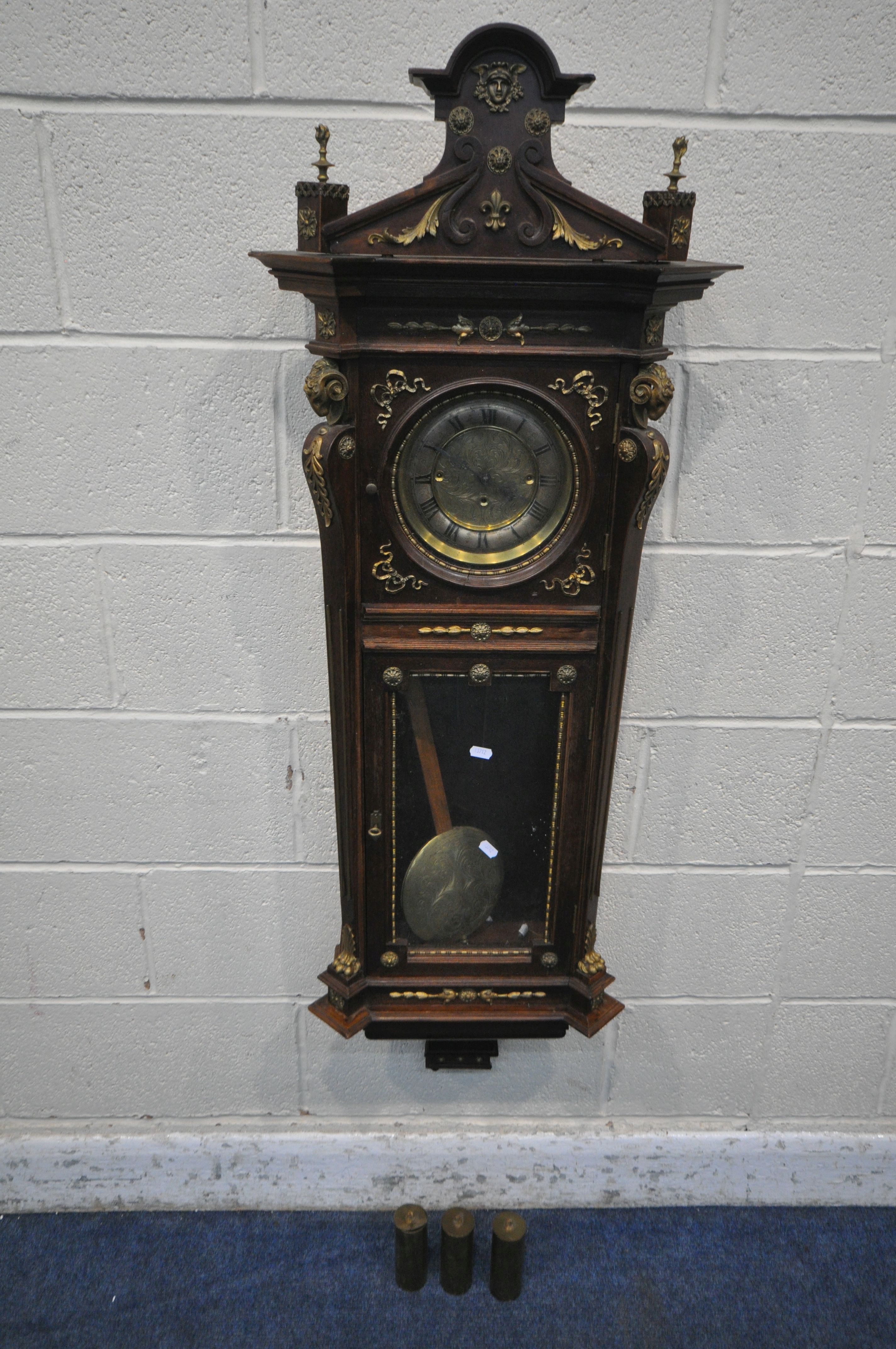 A 20TH CENTURY OAK CASED WALL CLOCK, with a variety of brass decorations, to include masks, ribbons,