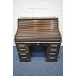 AN EARLY 20TH CENTURY OAK ROLL TOP DESK, enclosing a fitted interior, on two pedestals, each with