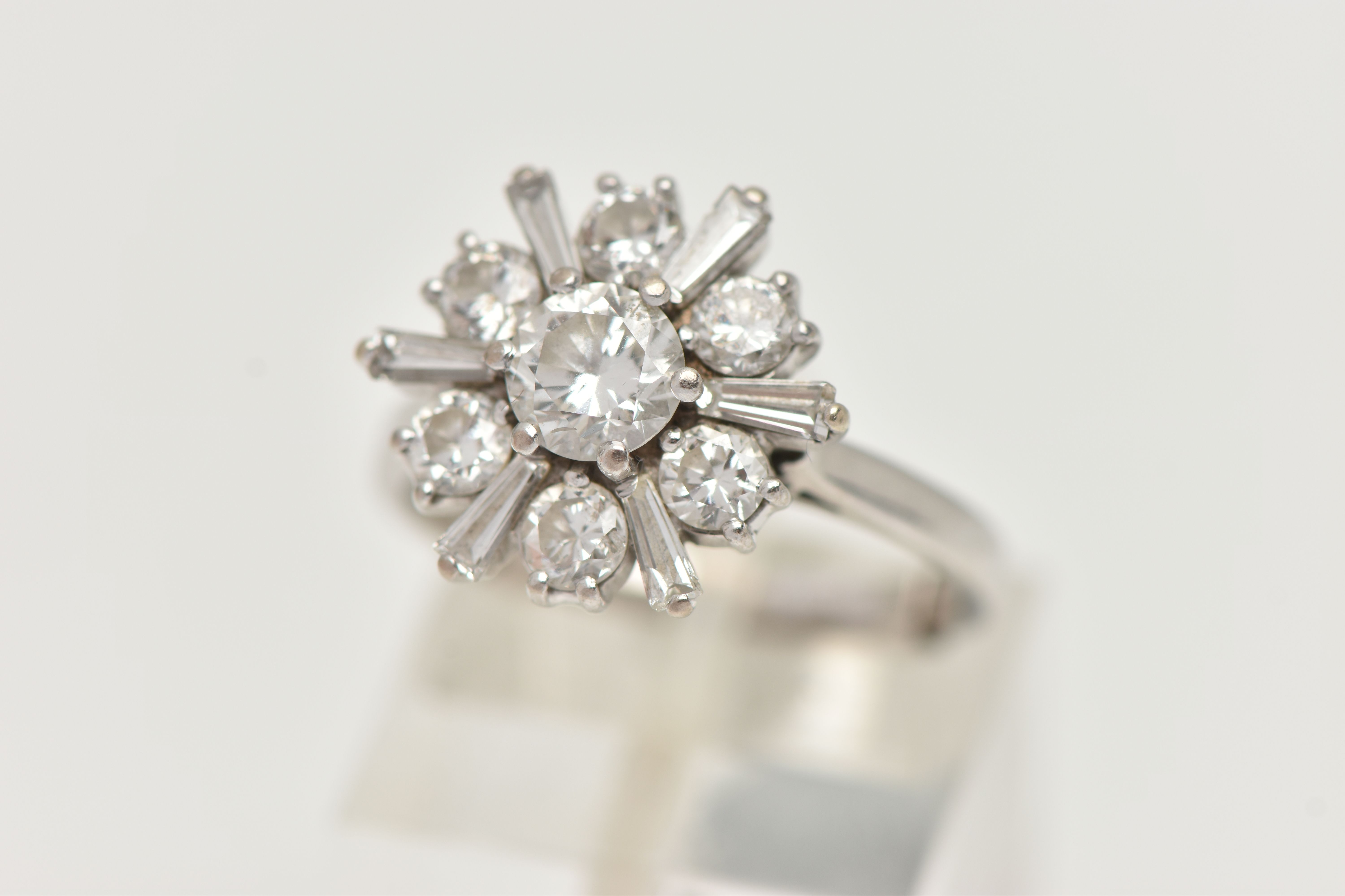 AN 18CT WHITE GOLD DIAMOND CLUSTER RING, centering on a round brilliant cut diamond, estimated