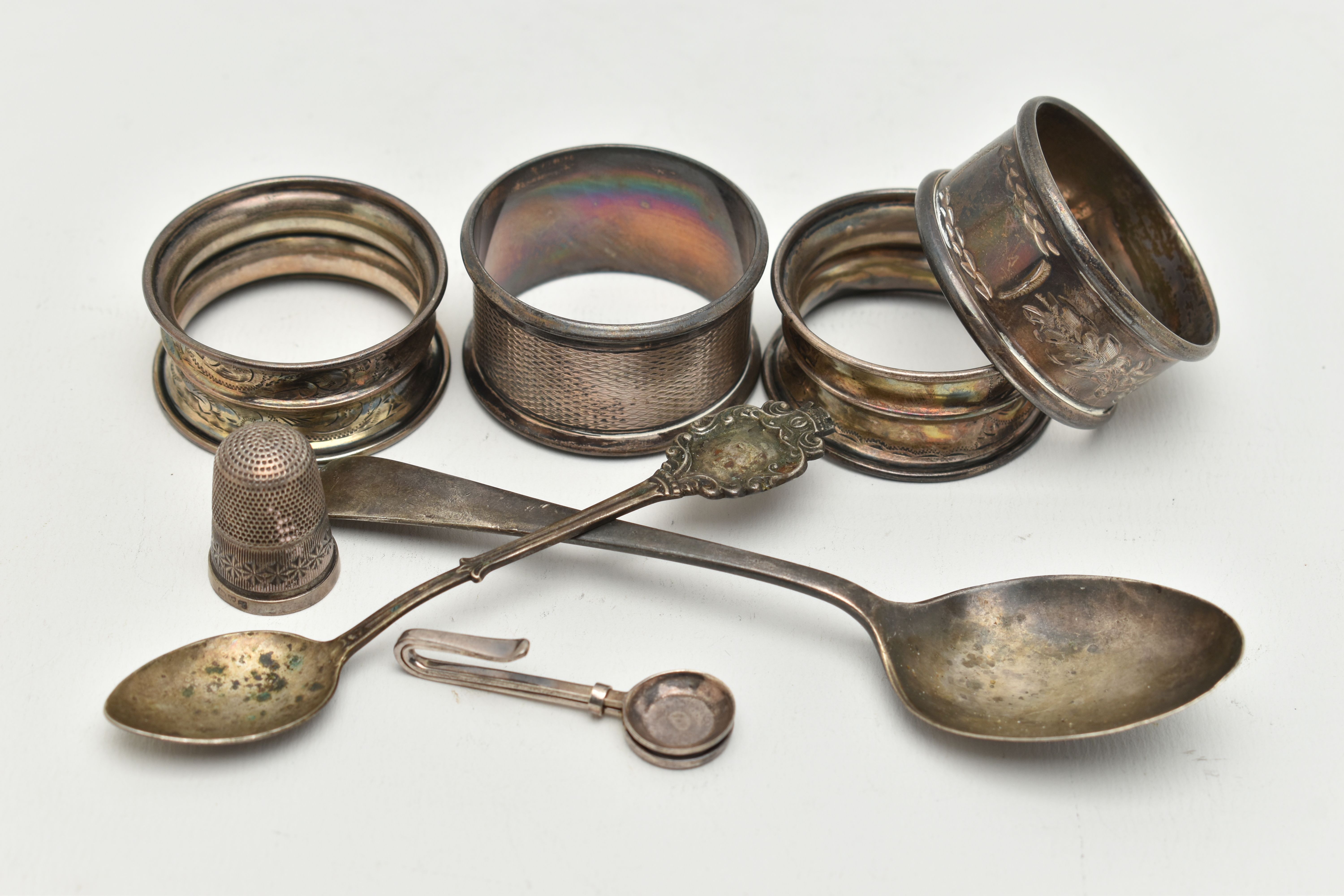 AN ASSORTMENT OF SILVER ITEMS, to include four silver napkin rings, a tea spoon, a spoon a thimble