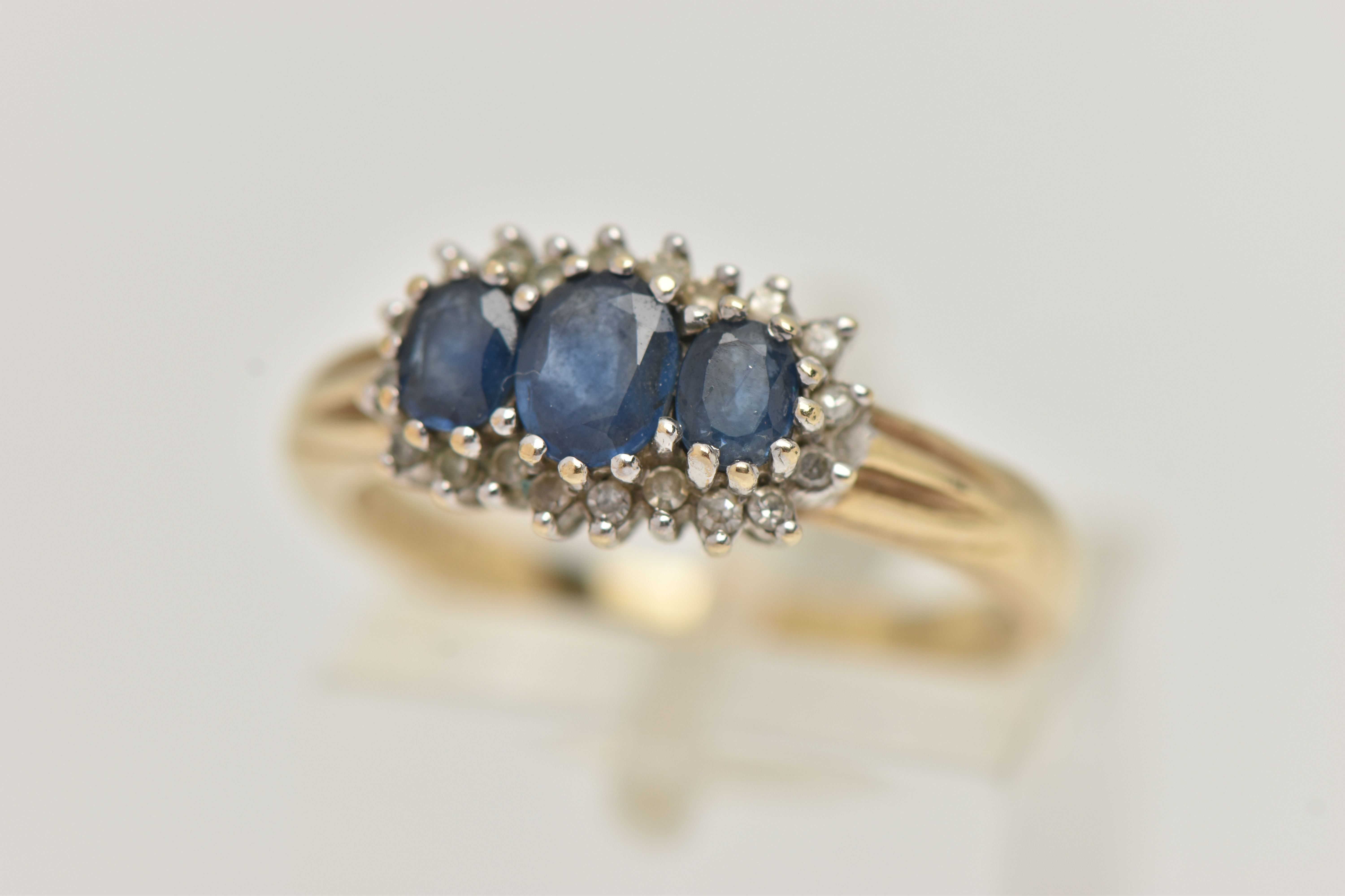 A 9CT GOLD SAPPHIRE AND DIAMOND RING, designed as three graduated oval sapphires within a single cut