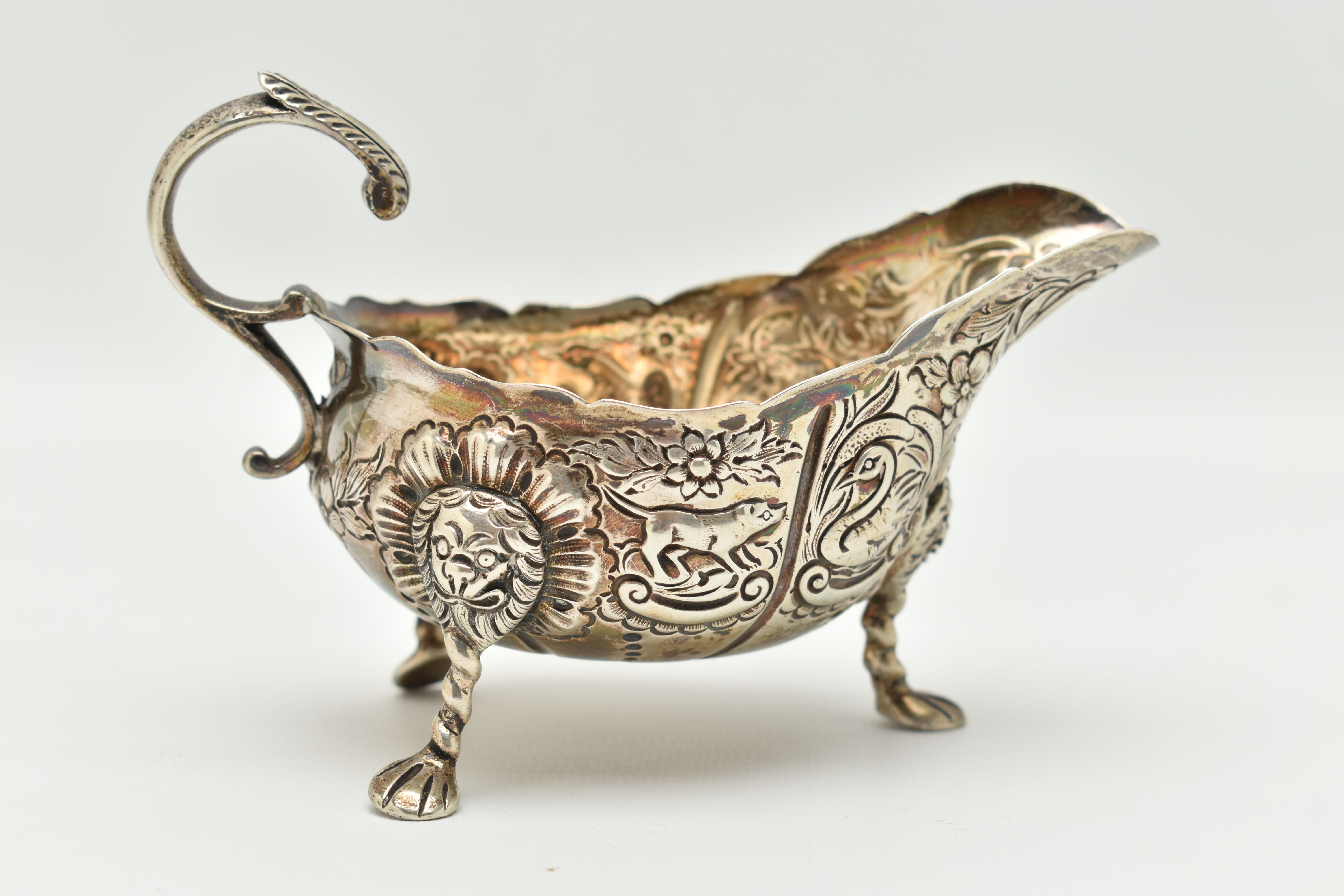 AN IRISH SILVER GRAVY BOAT, early 20th century, embossed animal and floral pattern, with three - Image 3 of 6