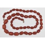 A BAKELITE CHERRY AMBER BEAD NECKLACE, a single strand of rectangular oval beads, largest bead