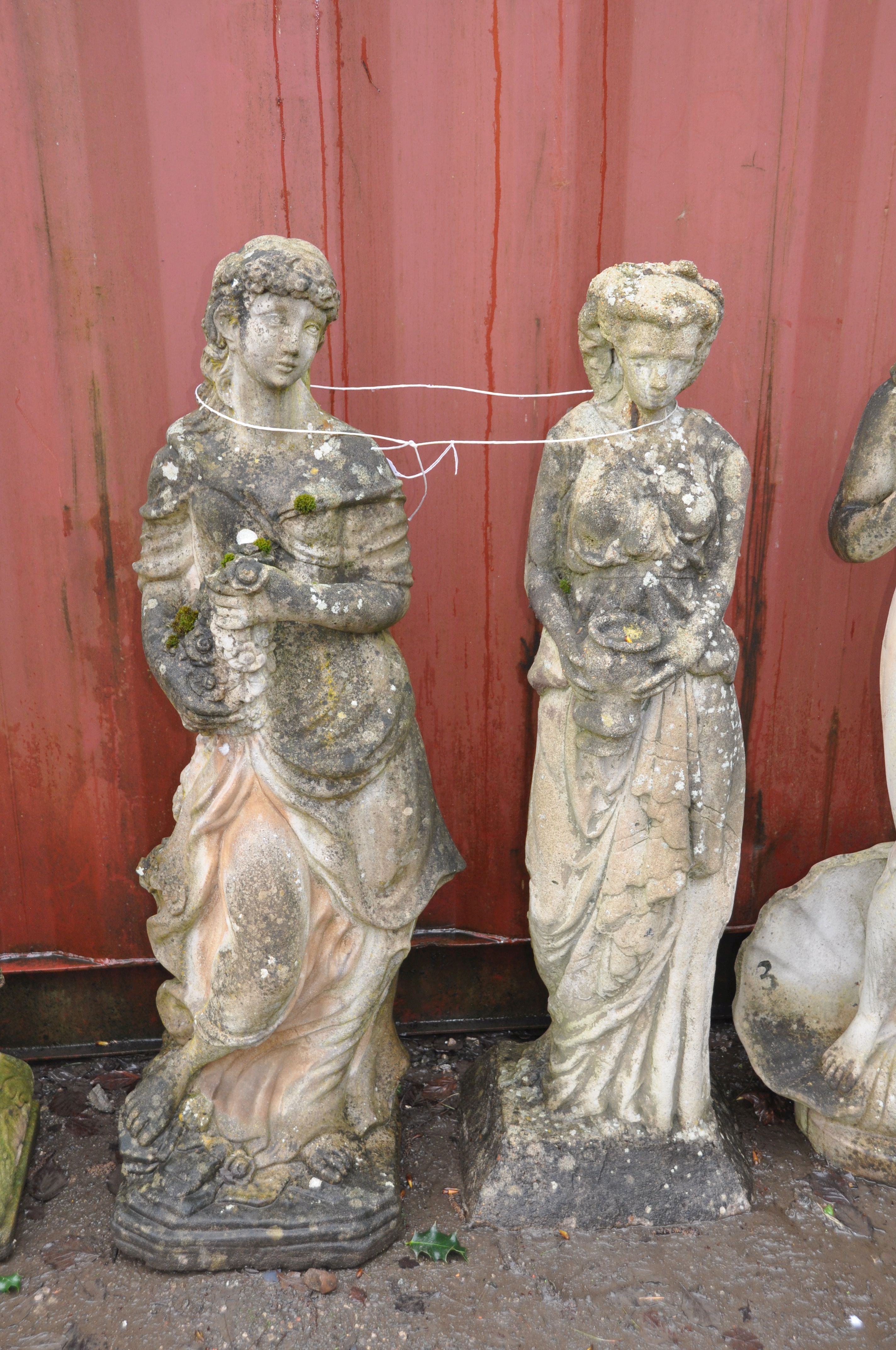 TWO WEATHERED COMPOSITE GARDEN FIGURES OF GRECIAN LADIES both standing one carrying flowers 118cm