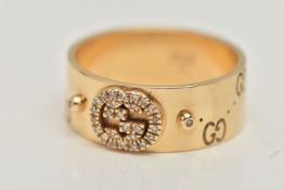 AN 18CT GOLD 'GUCCI' ICON BAND RING, a wide yellow metal band with a repetitive 'Gucci' logo and a