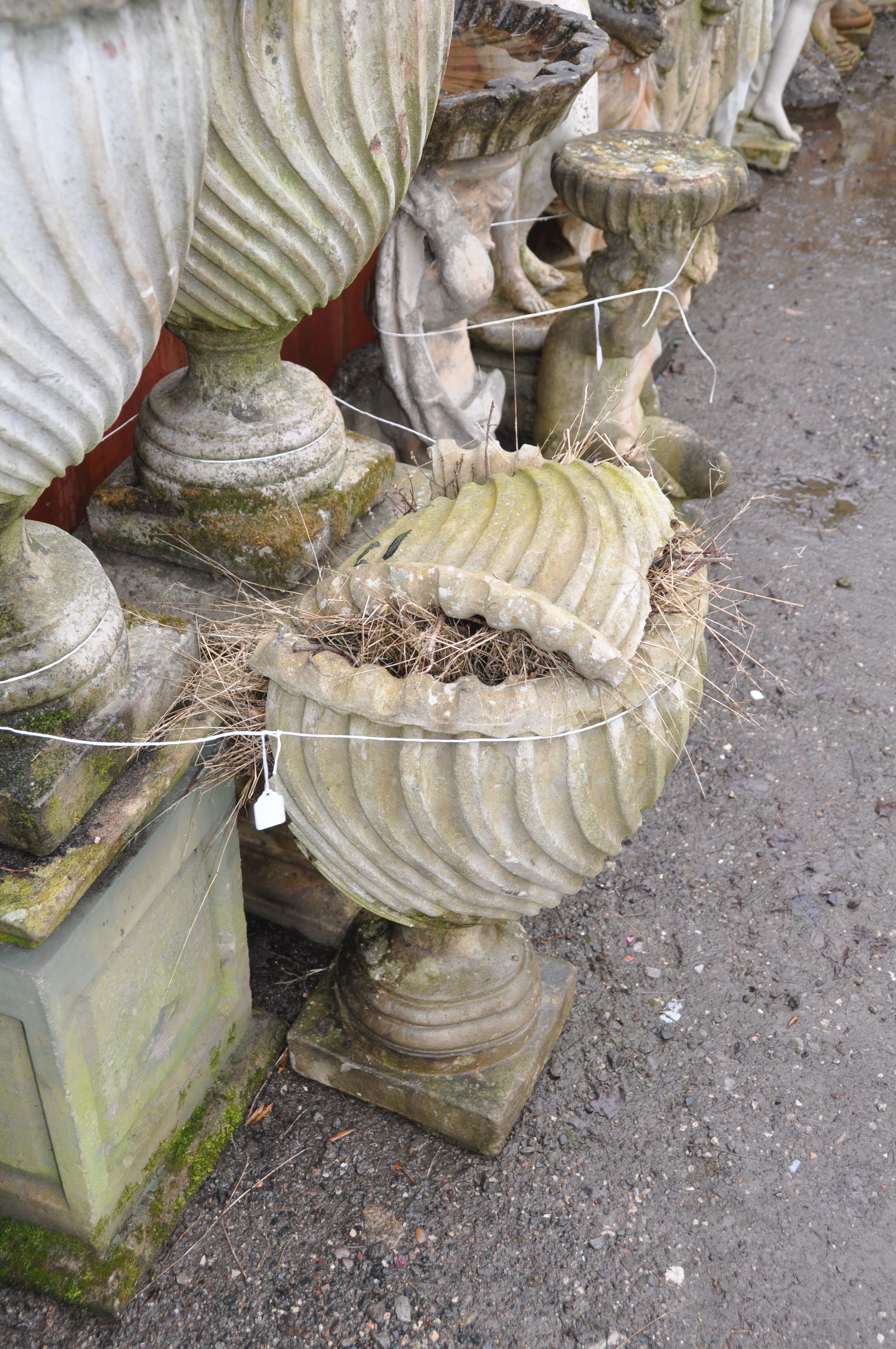 A PAIR OF WEATHERED COMPOSITE SPIRAL FLUTED GARDEN URNS mounted on two different square bases and - Image 3 of 3