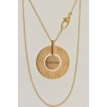 A 'GUCCI' ICON NECKLACE, a yellow metal circular disk pendant with a moveable central disk,