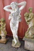 A WEATHERED COMPOSITE GARDEN FIGURE of a SCANTILY clad lady posing with her hands on her head,