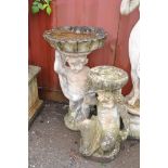 TWO WEATHERED COMPOSITE GARDEN FIGURES DEPICTING PUTTI one seated resting a bowl on its head (some