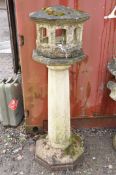 A WEATHERED COMPOSITE ORIENTAL STYLE BIRD HOUSE with octagonal tapering column beneath an