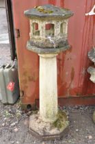 A WEATHERED COMPOSITE ORIENTAL STYLE BIRD HOUSE with octagonal tapering column beneath an