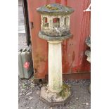 A WEATHERED COMPOSITE ORIENTAL STYLE BIRD HOUSE with octagonal tapering column beneath an