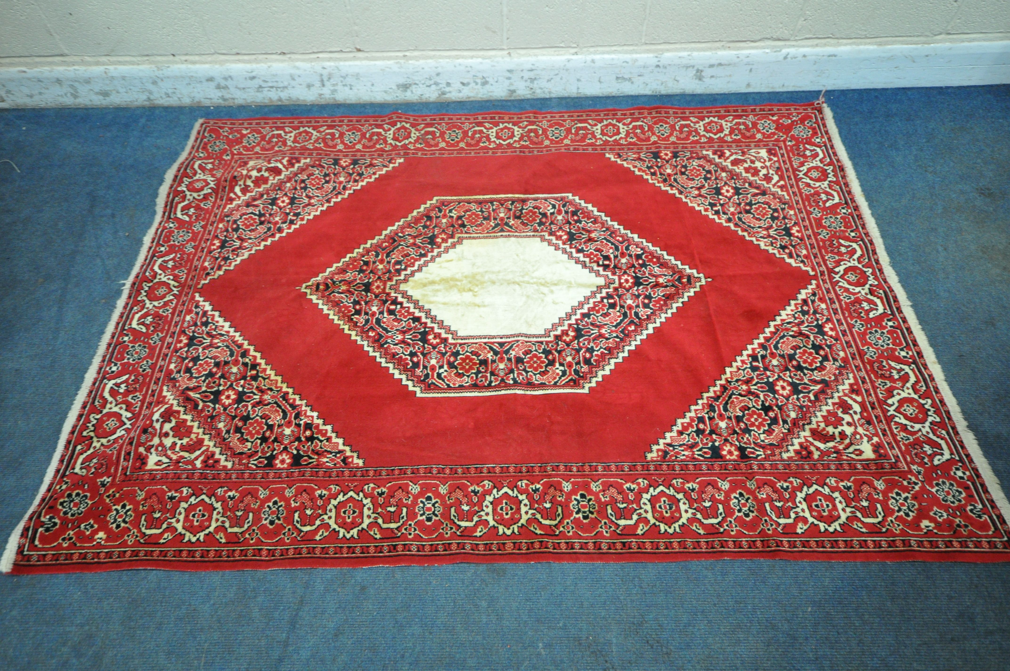 A RED GROUND SYNTHETIC SILK RUG, with central medallion, foliate designs and multi-strap border,